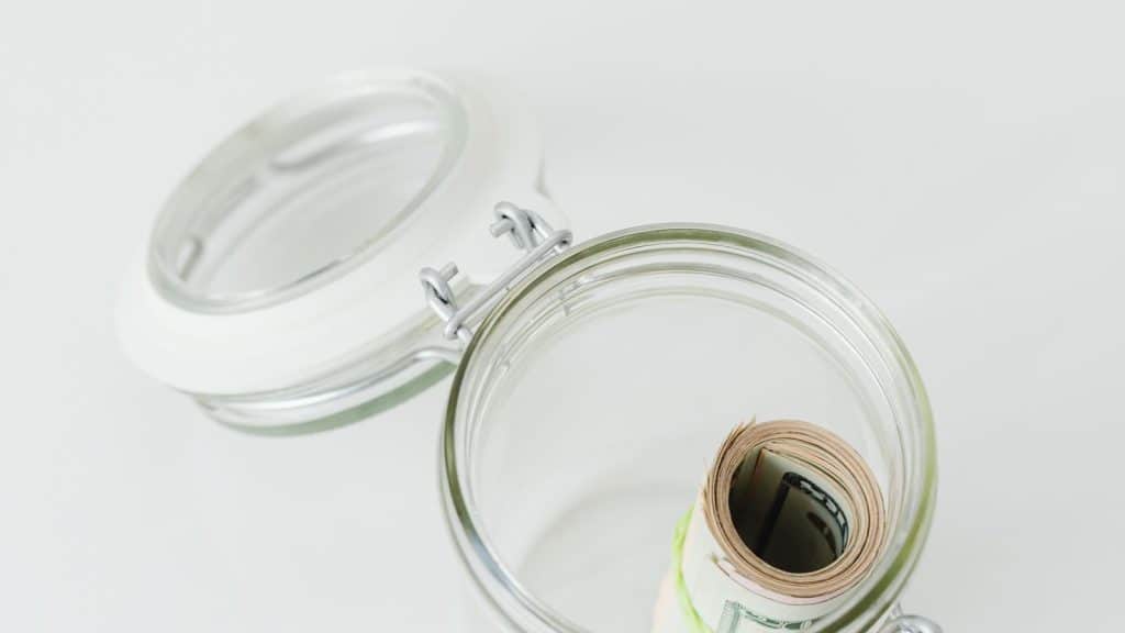 Billets de dollars roulés dans un bocal en verre ouvert : épargne retraite américaine imposée en France